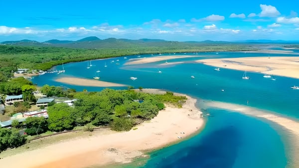 Luftaufnahme einer tropischen Bucht mit klaren türkisfarbenen Wassern und Segelbooten auf dem Gelände von Gladstone High School.