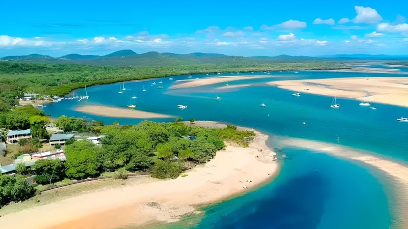 Luftaufnahme einer tropischen Bucht mit klaren türkisfarbenen Wassern und Segelbooten auf dem Gelände von Gladstone High School.