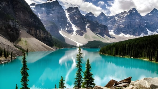 Ein türkisfarbener Bergsee vor schneebedeckten Gipfeln umgeben von immergrünen Wäldern nahe dem Glebe Collegiate Institute.