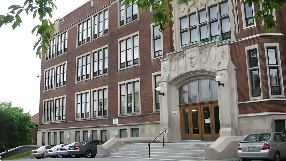Das mehrstöckige Backsteingebäude des Glebe Collegiate Institute ist von Bäumen und parkenden Autos umgeben.