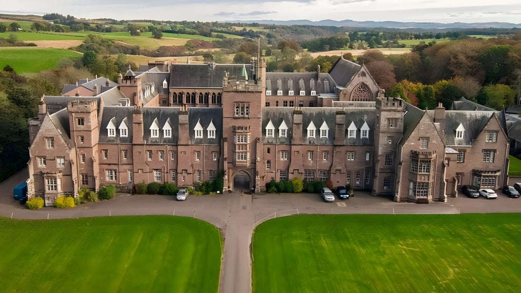 Das historische Schlossgebäude des Glenalmond College steht in einer weitläufigen Landschaft mit gepflegten Rasenflächen und Gärten.