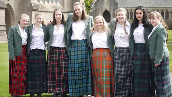 Eine Gruppe Schülerinnen in Schuluniformen steht vor einem historischen Gebäude auf dem Campus des Glenalmond College.