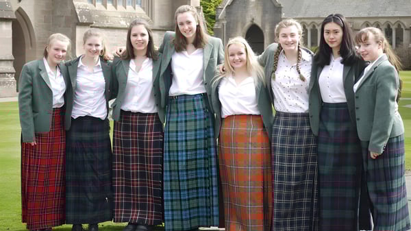Eine Gruppe von Schülerinnen in Uniform steht vor einem historischen Gebäude auf dem Campus des Glenalmond College.