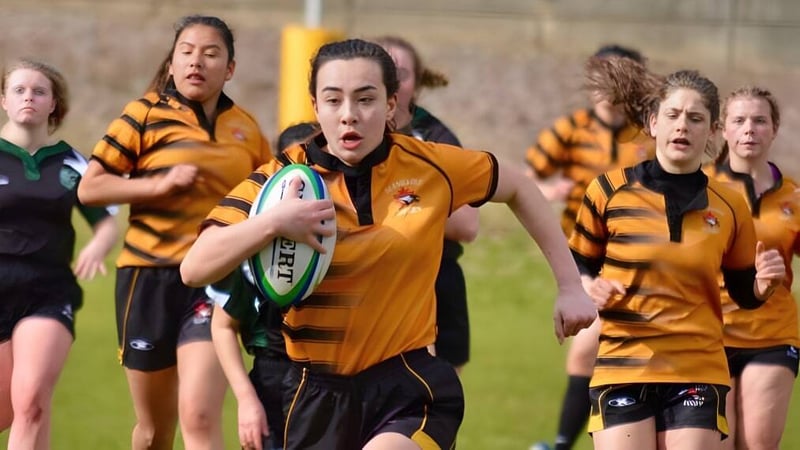 Eine Gruppe von Rugbyspielerinnen läuft auf dem Spielfeld der Gleneagle Secondary School.