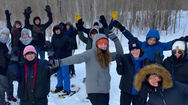 Schüler der Glengarry District High School stehen im verschneiten Wald und feiern gemeinsam.