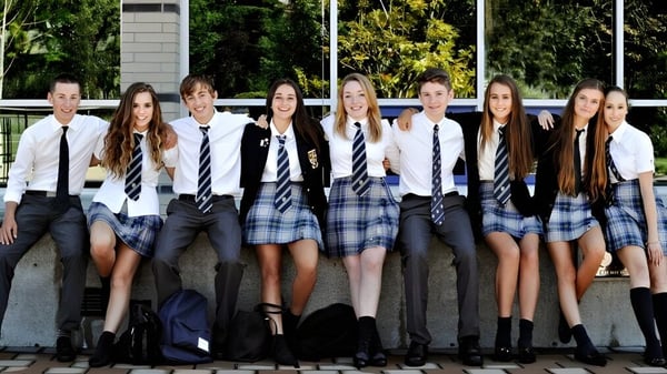 Eine Gruppe Schüler steht auf dem Gelände der Glenlyon Norfolk School vor Gebäuden und Grünflächen.