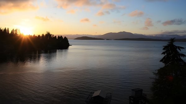 Ein ruhiger See mit immergrünen Wäldern und Bergen im Hintergrund bei Sonnenuntergang auf dem Campus der Glenlyon Norfolk School.