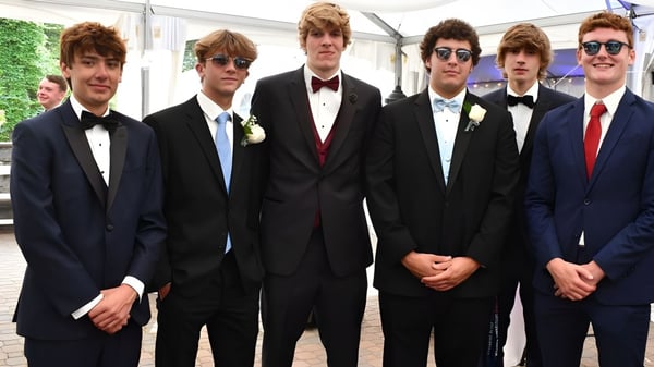 Eine Gruppe junger Männer in formeller Kleidung steht draußen auf dem Gelände der Glenstal Abbey School.