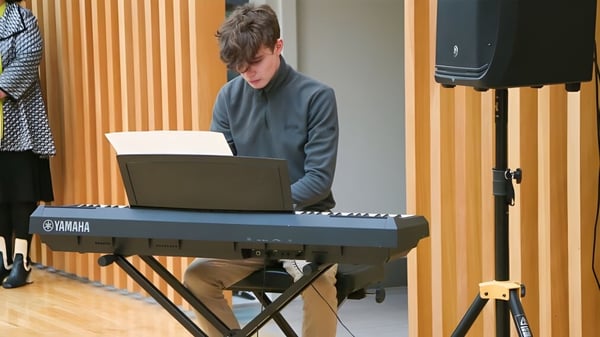 Eine Person spielt Keyboard im Musikraum der Glenstal Abbey School mit holzverkleideten Wänden.