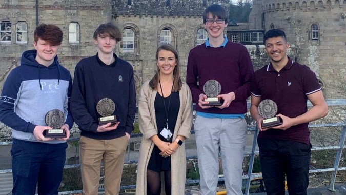 Fünf Schüler der Glenstal Abbey School stehen vor einem historischen Steinbau und halten Auszeichnungen.