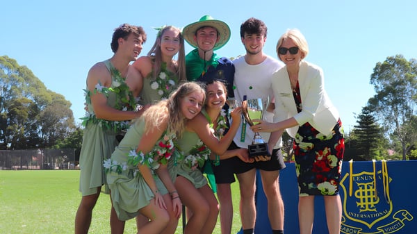 Eine Gruppe Schülerinnen und Schüler der Glenunga International High School steht auf einer Wiese vor Bäumen.