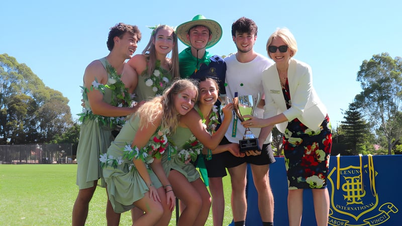 Eine Gruppe Schülerinnen und Schüler der Glenunga International High School steht auf einer Wiese vor Bäumen.
