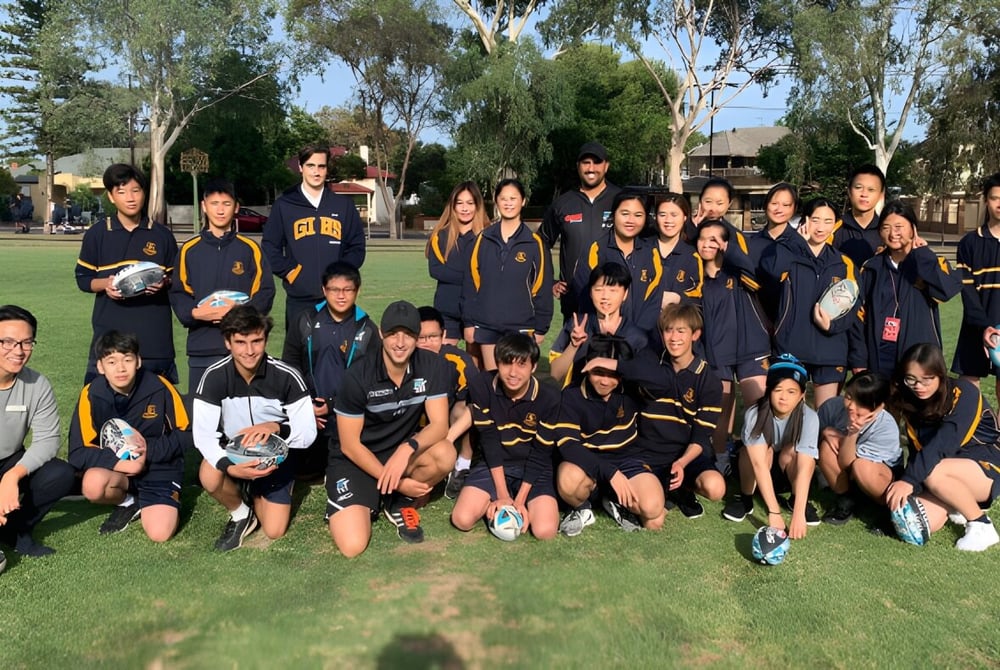 Die Sportmannschaft der Glenunga International High School posiert gemeinsam auf einem grasbewachsenen Spielfeld mit Bäumen im Hintergrund.