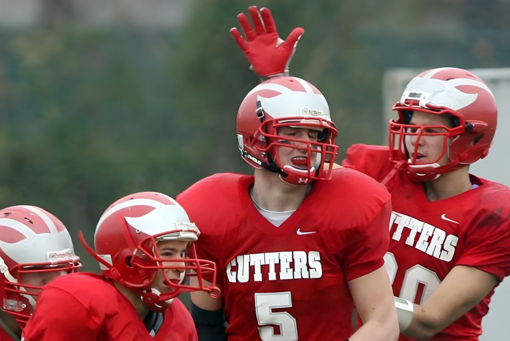 Eine Gruppe von Fußballspielern in roten Trikots steht auf dem Spielfeld der Gloucester High School.