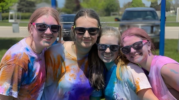 Eine Gruppe junger Frauen in bunten Batikshirts posiert gemeinsam im Freien auf dem Gelände der Goderich District Collegiate Institute.