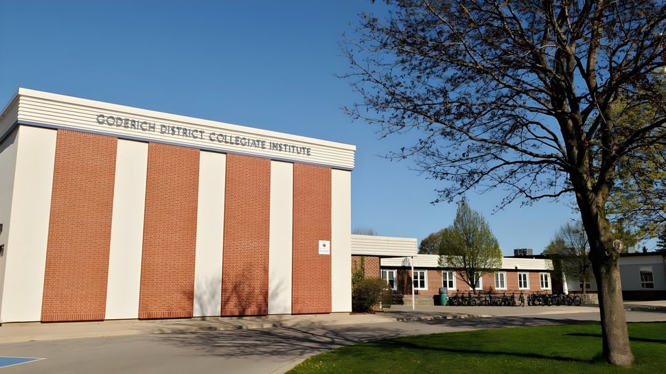 Das Backsteingebäude des Goderich District Collegiate Institute steht umgeben von einer Wiese mit einem Baum im Vordergrund.