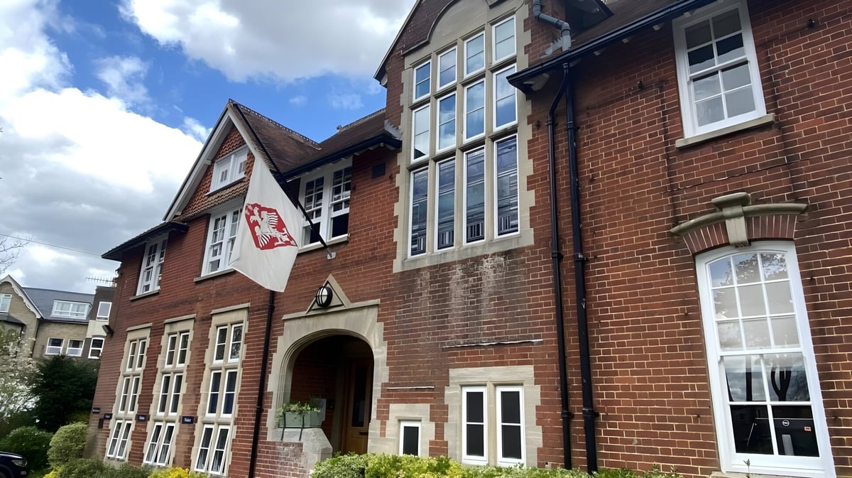 Das mehrstöckige Backsteingebäude der Godolphin School mit großen Fenstern und einem gewölbten Haupteingang vor bewölktem Himmel.