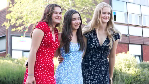 Drei Schülerinnen der Godolphin School stehen zusammen vor einem Gebäude mit Grünpflanzen im Hintergrund.