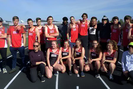 Eine Gruppe von jungen Athletinnen und Athleten der Golden Secondary School posiert gemeinsam auf der Laufbahn mit Bergen im Hintergrund.