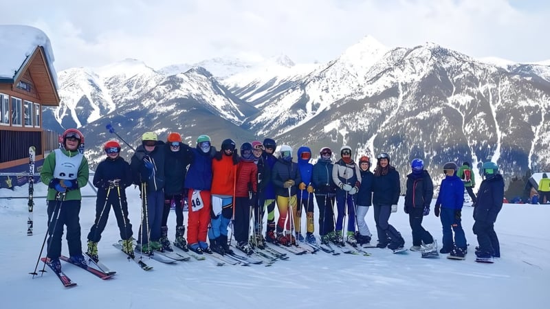Eine Gruppe von Schülern der Golden Secondary School steht bei Winterbekleidung auf einem schneebedeckten Hang vor einer Berglandschaft.