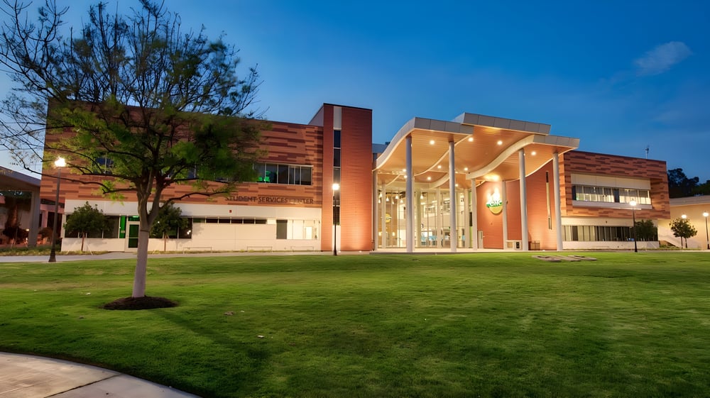 Das moderne Gebäude mit Glasfassade auf dem Campus des Golden West College ist von gepflegtem Rasen und Bäumen umgeben.