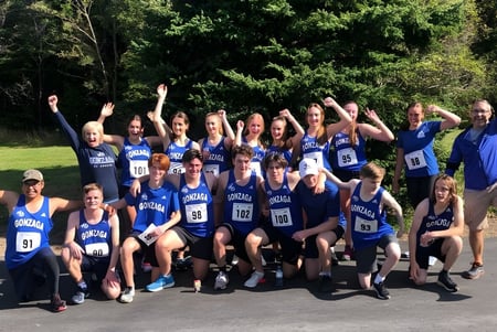 Eine Gruppe von Schülerinnen und Schülern der Gonzaga High School posiert zusammen im Wald während einer Sportveranstaltung.