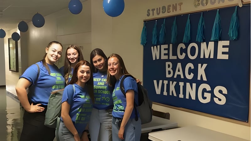 Schülerinnen und Schüler der Gonzaga High School stehen lächelnd im Schulflur vor einem Willkommensbanner mit blauen Luftballons.