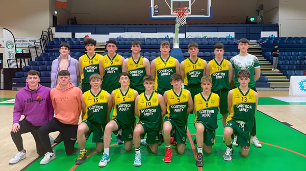 Eine Gruppe von Schülerinnen und Schülern der Gortnor Abbey posiert gemeinsam auf dem Basketballfeld mit Korb im Hintergrund.