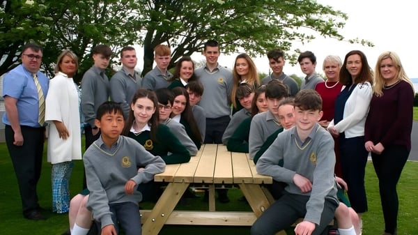 Eine Gruppe von Schülern sitzt um einen Holztisch im Freien auf dem Campus der Gortnor Abbey School.