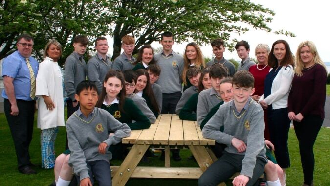 Eine Gruppe Schülerinnen und Schüler der Gortnor Abbey versammelt sich draußen auf einer Wiese mit Bäumen im Hintergrund.