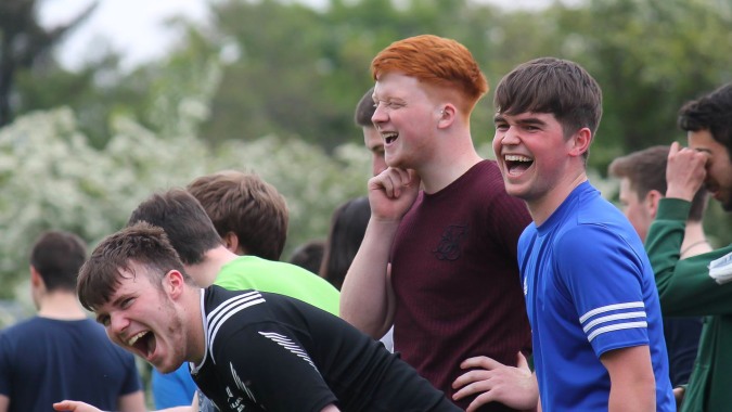 Eine Gruppe von Schülern der Gortnor Abbey steht lachend im Freien vor Bäumen und Grünfläche.