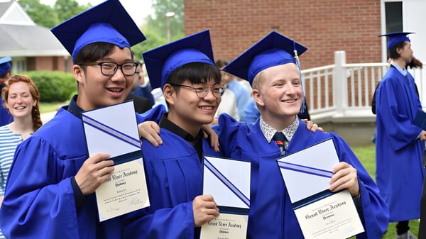 Eine Gruppe von Absolventen der Grand River Academy steht mit blauen Hüten und Roben vor einem Backsteingebäude und hält ihre Diplome.