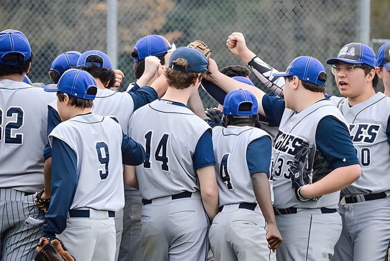 Schüler der Grand River Academy feiern gemeinsam auf dem Baseballfeld mit Mannschaftskameraden im Hintergrund.