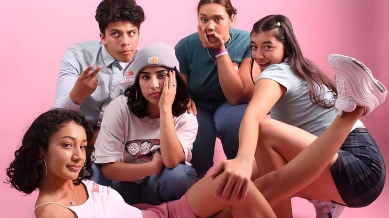 Eine Gruppe von Schülerinnen und Schülern der Grand Arts - Ramon C. Cortines School of Visual and Performing Arts posiert gemeinsam vor einem pinken Hintergrund.