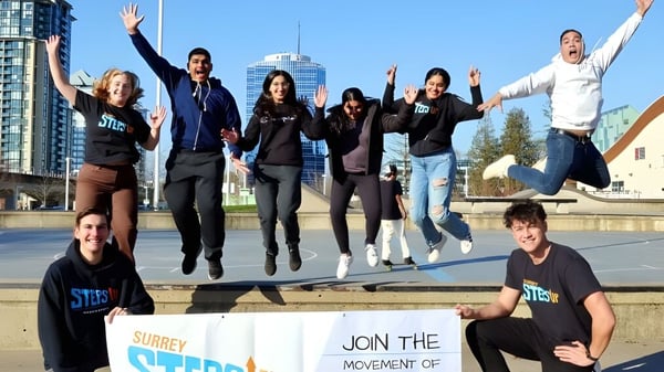 Schüler der Grandview Heights Secondary School springen und feiern vor einer modernen Stadtkulisse.