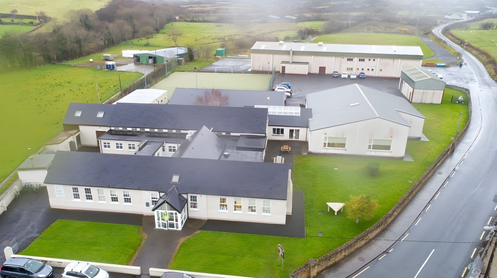 Das mehrstöckige Hauptgebäude der Grange Post Primary School steht auf einer Wiese, umgeben von kleineren Gebäuden und einer Straße.