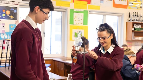 Zwei Schüler unterhalten sich im Klassenzimmer der Grange Post Primary School vor Lehrmaterialien.