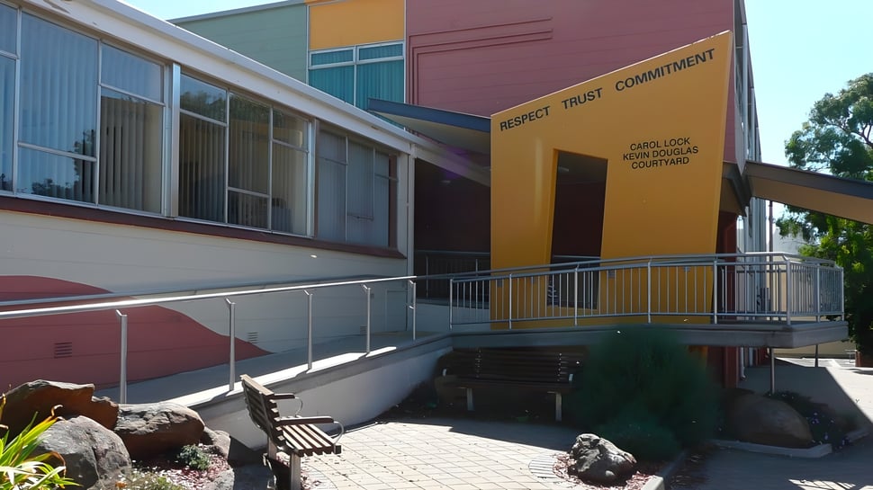 Das moderne Gebäude der Grant High School zeigt einen Eingang mit Rampe und eine natürliche Landschaft mit Steinen und Pflanzen.