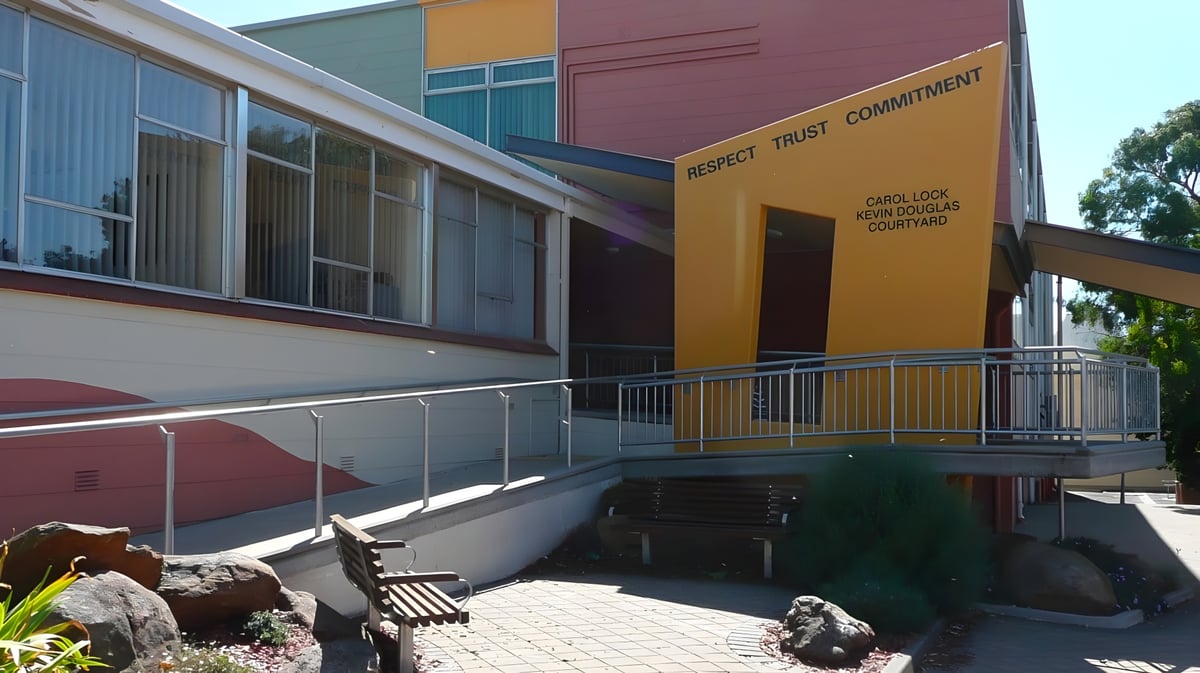 Das moderne Gebäude der Grant High School zeigt einen Eingang mit Rampe und eine natürliche Landschaft mit Steinen und Pflanzen.