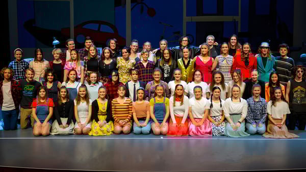 Eine Gruppe Schüler versammelt sich auf der Bühne der Grant High School vor dunklem Hintergrund.