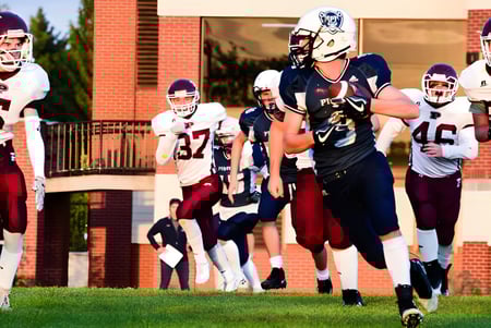 Eine Gruppe von Fußballspielern in Uniform steht vor einem Backsteingebäude auf dem Campus der Grant Park High School.