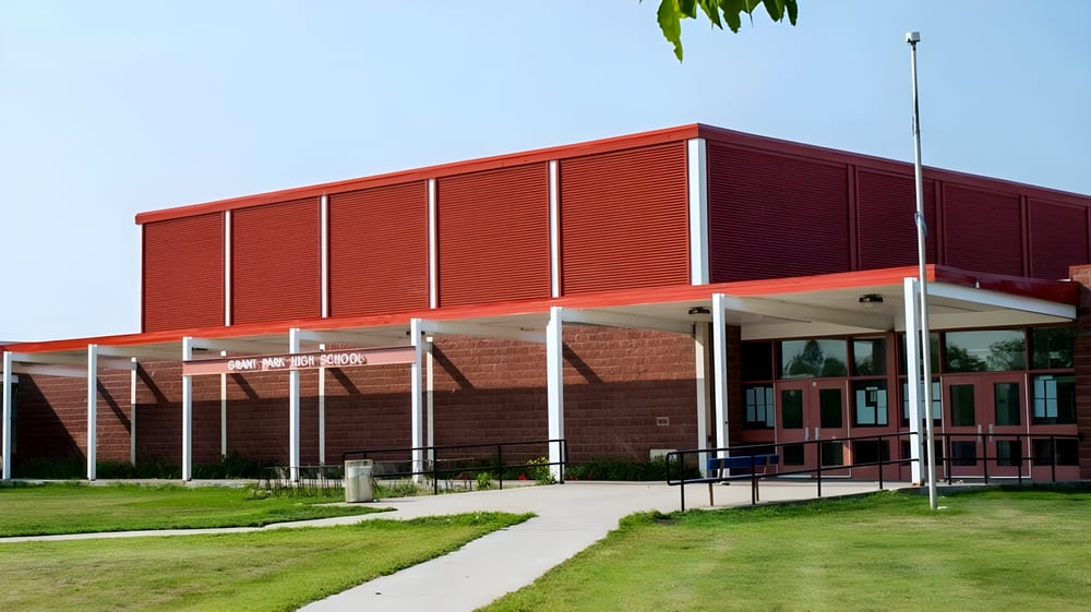 Das rote Gebäude von Grant Park High School mit überdachtem Eingang und Grünfläche im Vordergrund unter klarem Himmel.