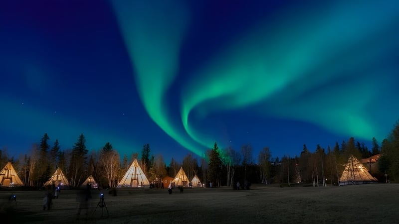 Die Nordlichter erhellen den Nachthimmel über einem Feld mit Tipis auf dem Gelände der Grant Park High School.