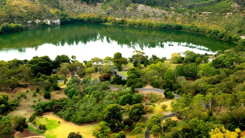 Eine grüne Landschaft mit einem ruhigen See und Wald im Hintergrund, nahe der Grant High School.