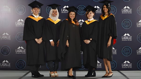 Eine Gruppe von Absolventinnen und Absolventen steht vor dem Logo des Great Lakes College of Toronto.