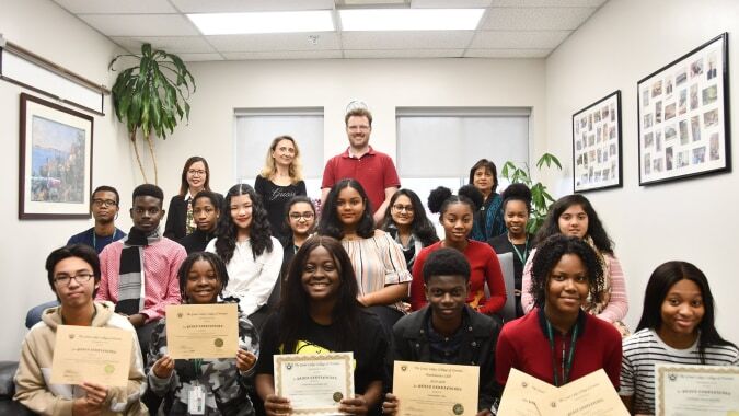 Eine Gruppe von Schülern des Great Lakes College of Toronto posiert mit einer Lehrkraft und Zertifikaten im Klassenzimmer.