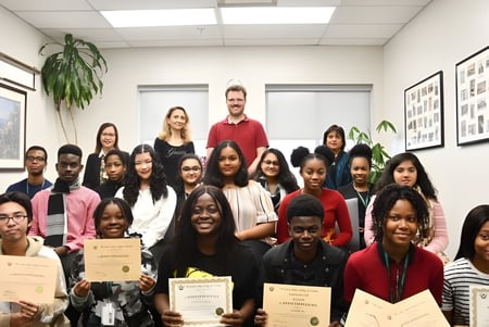 Eine Gruppe von Schülerinnen und Schülern des Great Lakes College of Toronto posiert mit Zertifikaten in einem Raum mit Kunstwerken.