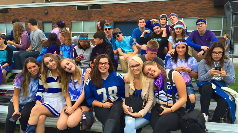 Eine Gruppe Schülerinnen und Schüler der Great Lakes District Secondary School steht vor einem Backsteingebäude.