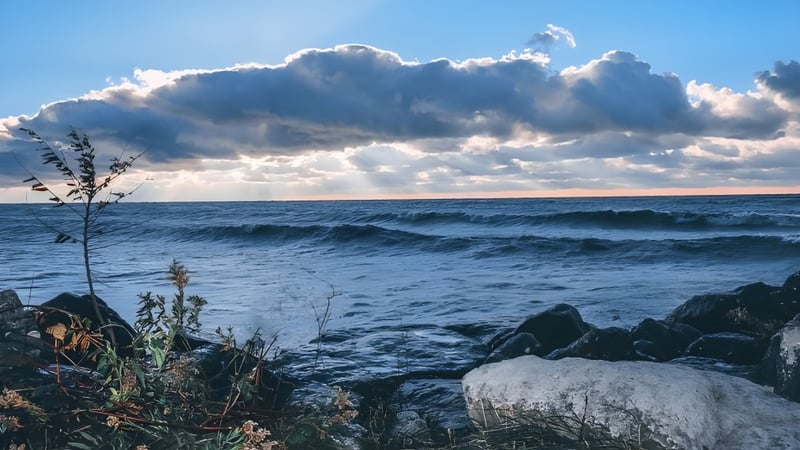 Dramatische Wellen schlagen an die felsige Küste unter einem bewölkten Himmel in der Nähe der Great Lakes District Secondary School.
