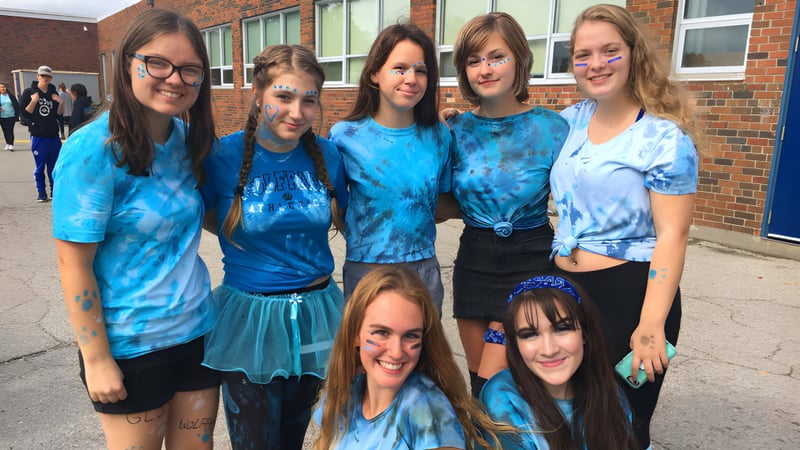 Eine Gruppe von Schülerinnen der Great Lakes District Secondary School steht vor einem Backsteingebäude.